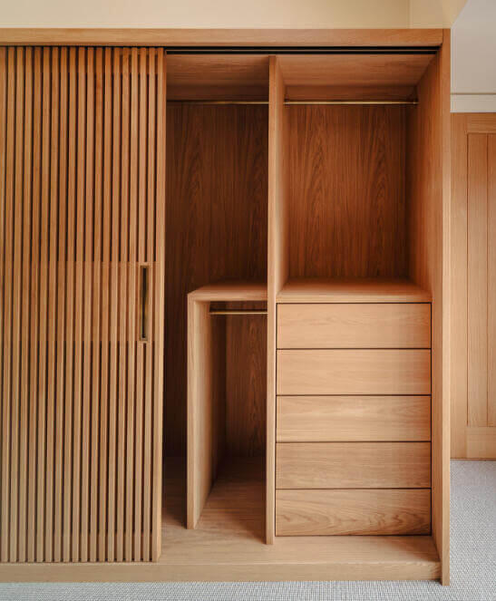 Commissioned bespoke wardrobe made from hand-selected solid European oak and veneers. Featuring oak sliding slatted doors, solid oak mitred drawers and naturally patinated brass hanging rail and recessed handle detail. Made by Fundi Joinery based in Edinbu