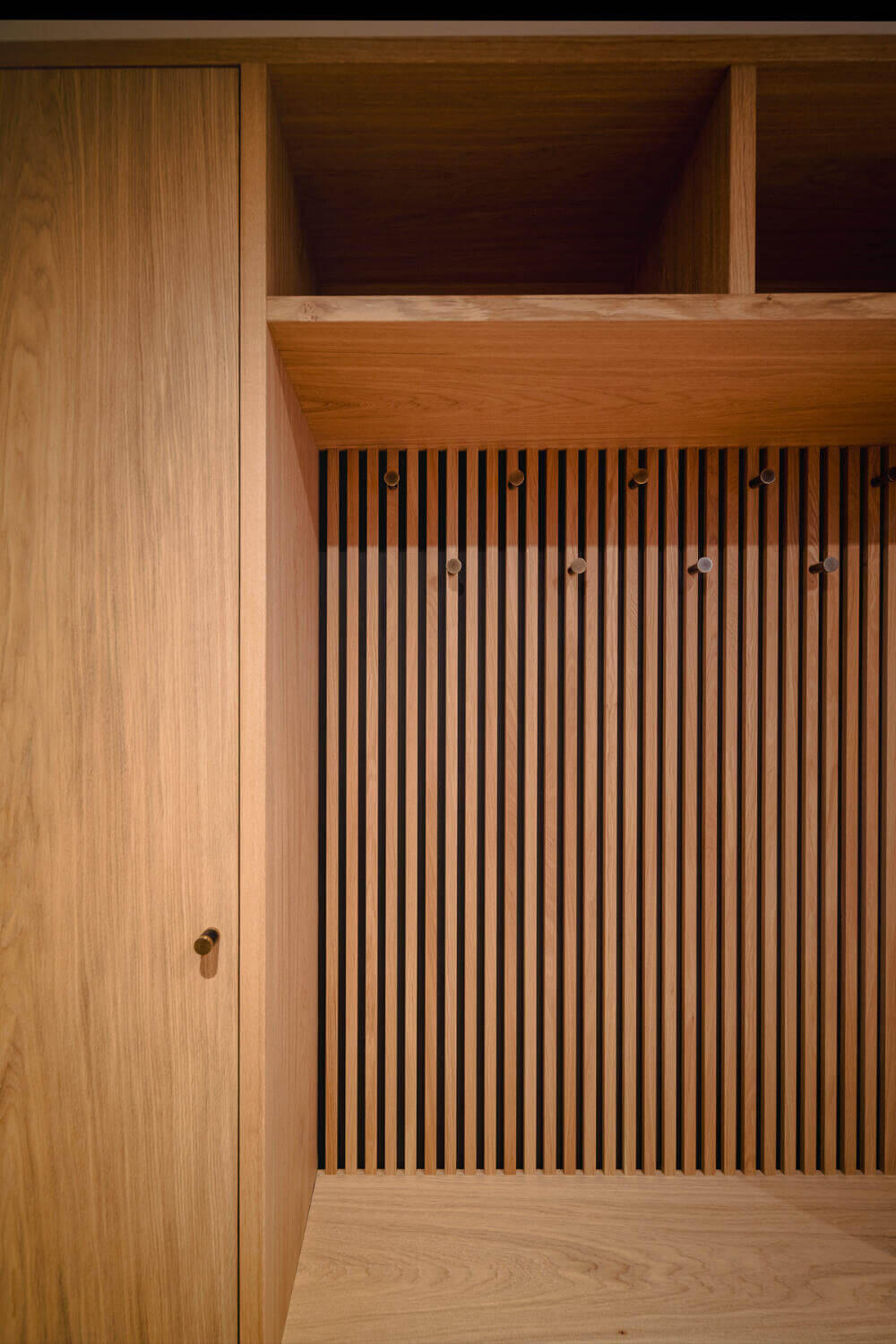 Bespoke Oak Boot Room Fitted Furniture Bespoke custom made boot room cabinetry from hand-selected European oak and veneers. Slatted back panels with black Valchromat and naturally patinated brass coat pegs. Made by Fundi Joinery in Edinburgh, Scotland